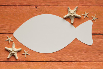 Paper sheet in the shape of the fish on wooden background