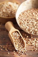 Buckwheat in scoop and bowl on wooden table