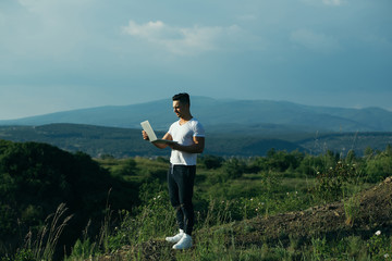 Pensive muscular man with laptop outdoor