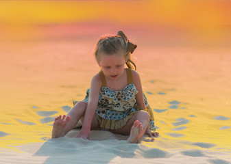 girl playing in the sand on the beach in the evening at sunset