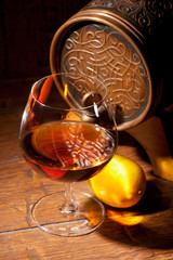 Glass of cognac with lemon on wooden background