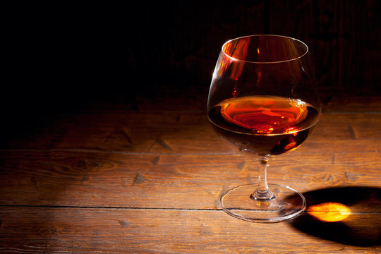 Glass of cognac with lemon on wooden background