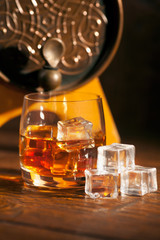 Glass of whiskey with ice on wooden table