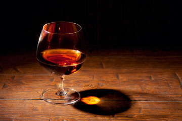 Glass of cognac with lemon on wooden background