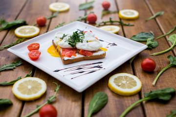 healthy breakfast with poached eggs royale (benedict). on background wooden table