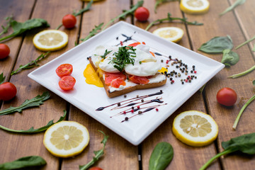 sandwich with fish and eggs for breakfast, on a dark wooden table
