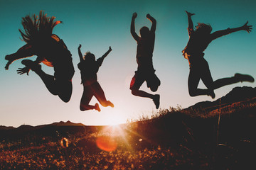 Four people jumping over the sky at sunset. Sunbeam in the background.