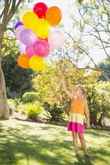 Fototapeta na wymiar Smiling girl holding with balloons in the park