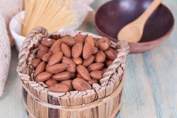 Almonds in brown bowl on textured wooden background
