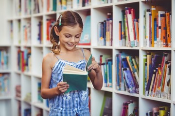 School girl reading a book in library
