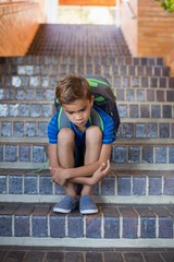 Sad schoolboy sitting alone on staircase