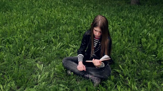 Young beautiful girl reading a book outdoor HD