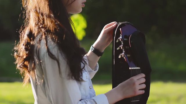 Girl's hands open a case and takes a guitar out of a case. Teen Girl remove beautiful wood  guitar out of a case.