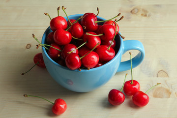 Obraz na płótnie Canvas heap of sweet cherries in Cup on wooden background
