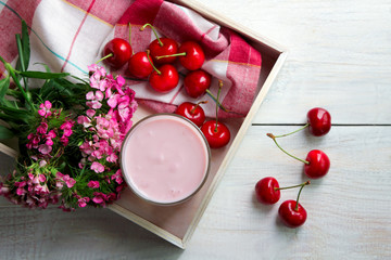 Naklejka na ściany i meble yogurt with taste of cherries in glass on wooden tray on a wooden background with flowers