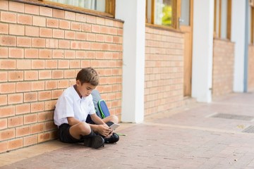 Schoolboy sitting in corridor and using mobile phone