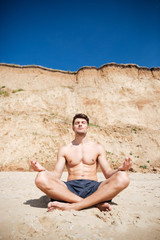 Naklejka na ściany i meble Man relaxing and meditating on the beach