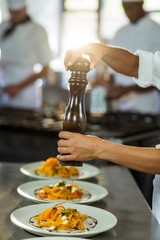 Chef sprinkling pepper on a meal