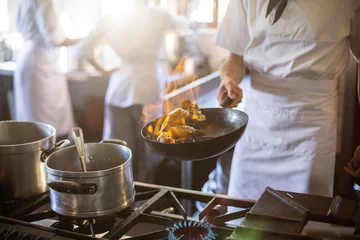 Fotobehang Koken Middengedeelte van chef-kok koken in keukenfornuis