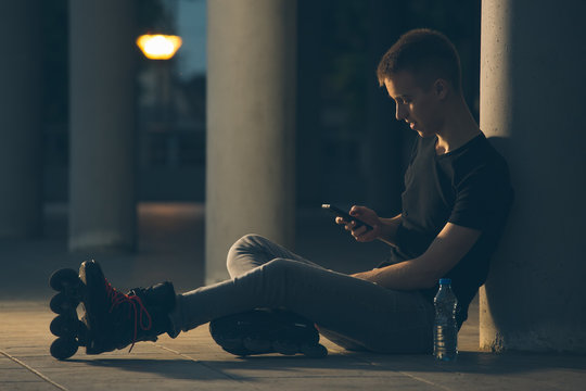 Rollerblader sitting and using mobile phone. night scene. 