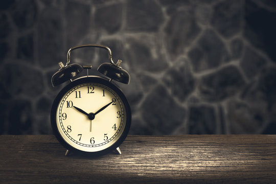 Alarm clock on wood with blurry stone walls in background