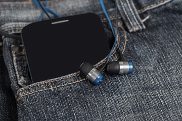earphones with mobile smartphone in the pocket old jeans