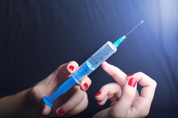 Medical injection on dark background. Medicine plastic vaccination equipment with needle. Health and care. Vaccination. Medicine background. Studio isolated. Phobia, Woman hand keep a injection