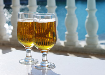 Two glasses of beer. Light beer in glasses on a white table against the sea.