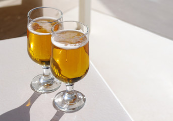 Two glasses of beer. Light beer in glasses on a white table.