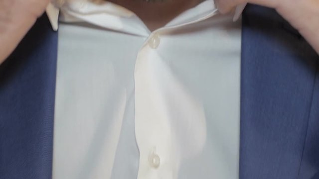 The man sit down and straightens his tie. Close up