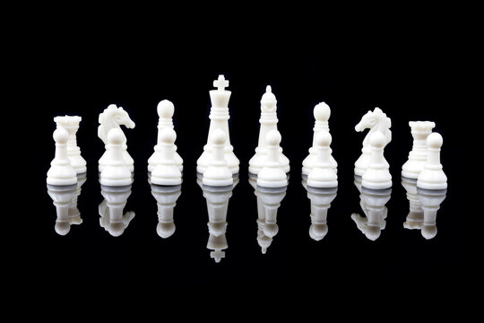 White chess pieces on black background with reflection