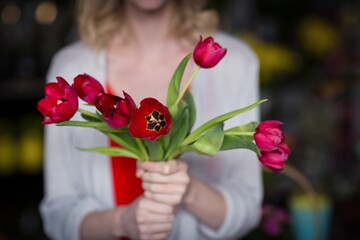 Female florist holding bunch of flower in flower shop