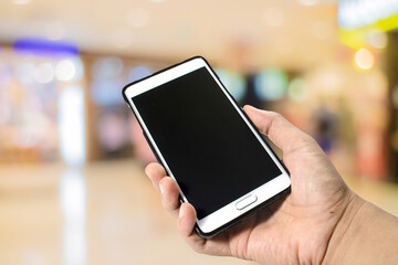 Hand hole smart phone on abstract blurred bookeh background