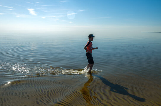 silhouette of happy teenager boy running on shore