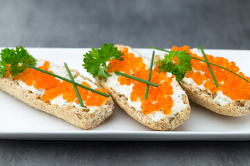 Red caviar on bread on white plate.