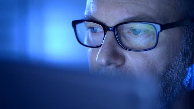 Closeup on one eye of a senior wearing glasses and looking at a computer screen.