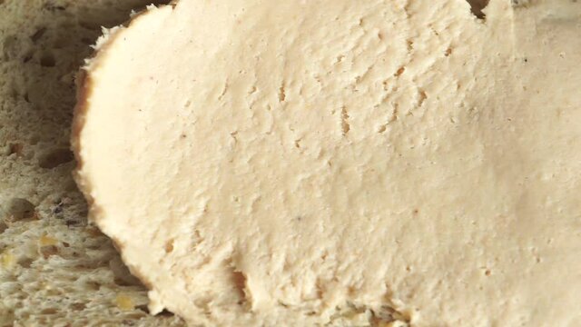 Macro video of butter being spread on bread, view from above