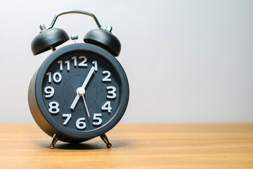 Black alarm clock place on wood table in burred background