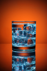 Close up of cold water glass with ice cubes.