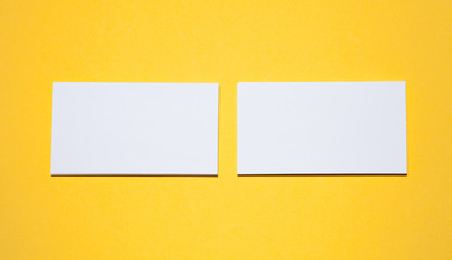 Empty business cards on yellow background - closeup shot