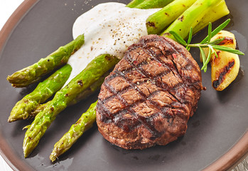 grilled beef steak and asparagus on dark plate
