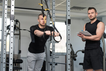 Trainer With Clipboard Man On Trx Fitness Straps