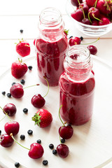 Two bottle of fresh strawberry blueberry smoothies on white wooden background. Selective focus
