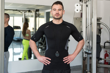 Fototapeta na wymiar Handsome Personal Trainer Standing Strong In A Gym
