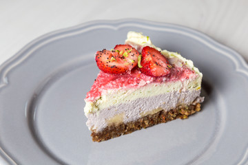 Raw vegan cake with strawberries and lime on a grey plate