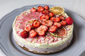 Raw vegan cake with strawberries and lime on a grey plate