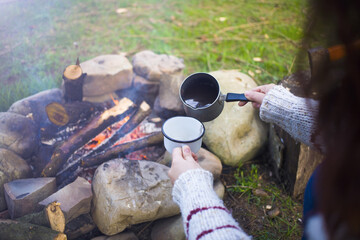 The girl prepares coffee in nature.