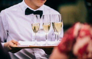 Professional male waiter in uniform serving champagne. DOF. Natural light. Photo in motion