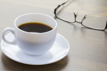 Obraz na płótnie Canvas Coffee Cup and Eyeglasses on Desktop