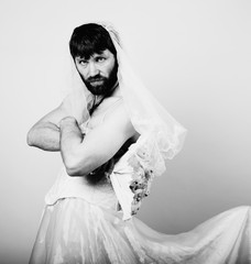bearded man in a woman's wedding dress on her naked body, holding a flower. funny bearded bride, black and white